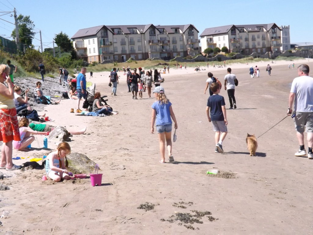 Photo de la plage de Hotwh en Irlande, le ciel est bleu et dégagé et des personnes profite de la plage.